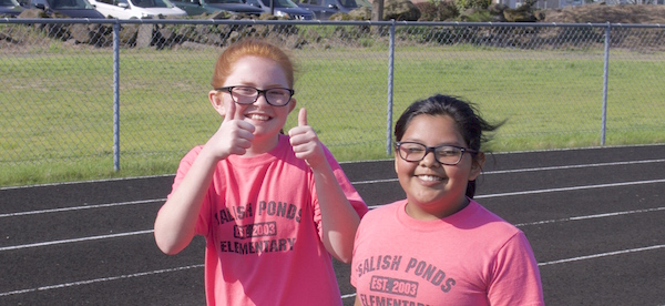 Girls on track smiling and thumbs up