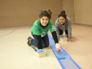 Students painting new lines on gym floor