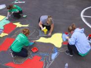 Volunteers and students painting the US map on the playground