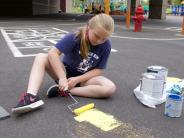 Student painting the US map on the playground