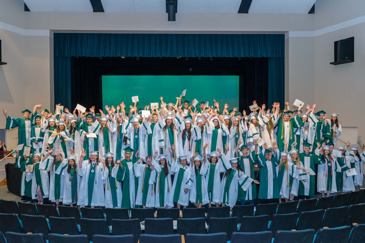 Senior Awards Night Honorees Seniors wearing green and white caps and gowns, waving hands and showing scholarship awards