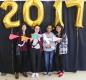Senior students holding paper pennants for the colleges they are to attend, with 2017 balloons behind them